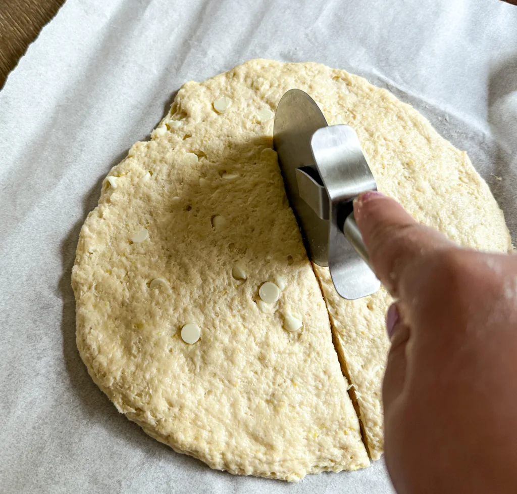 A pizza cutter slicing through some sourdough scone dough.