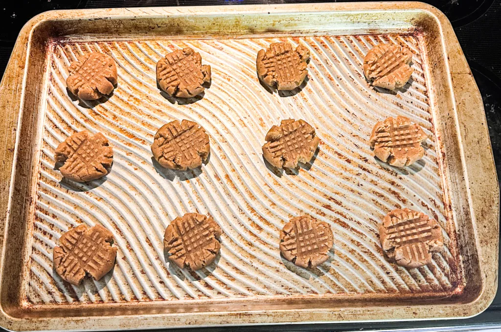 Egg-free peanut butter cookies fresh out of the oven on a cookie sheet.