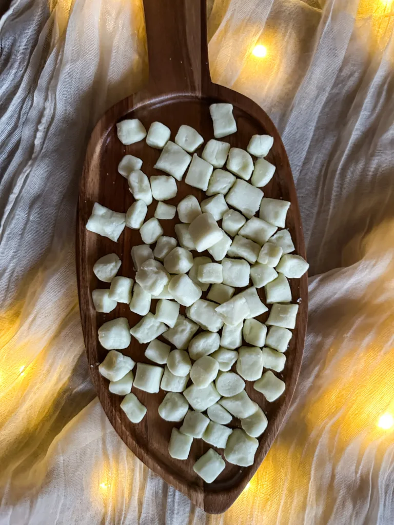 Butter mints on a wood cutting board on top of a table cloth with lights.