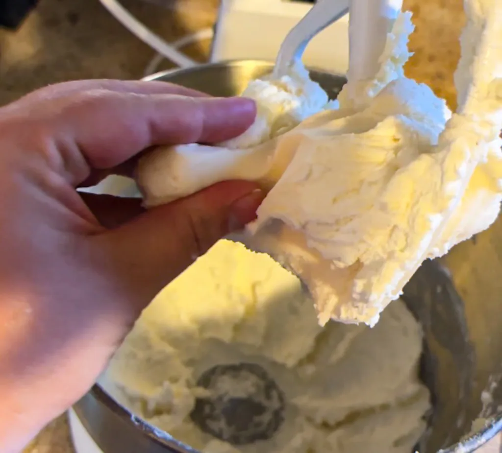 A hand feeling the texture of butter mint dough.