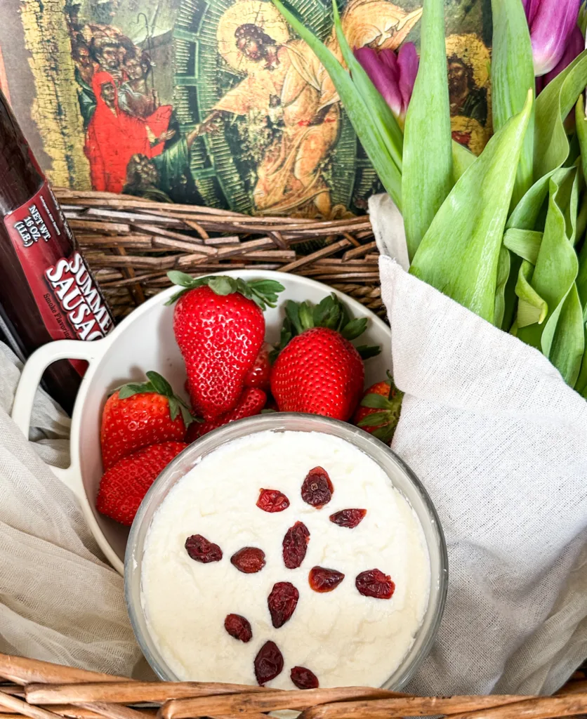 A traditional Easter basket with, food, flowers, and an icon.