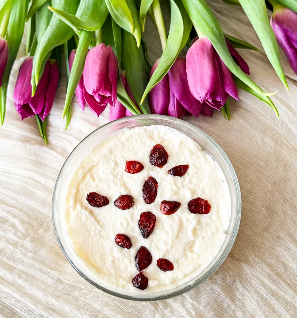 Cheese Pascha on a white table cloth, next to some tulips.