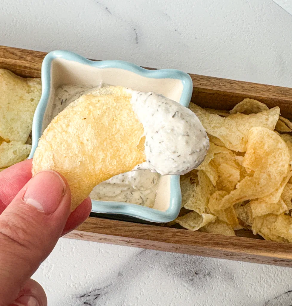 A hand holing a chip to eat.