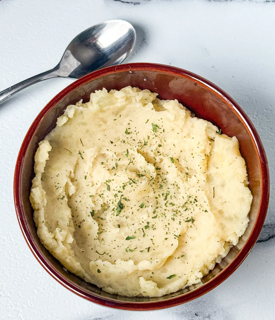 Dairy-free mashed potatoes in a bowl next to a spoon.