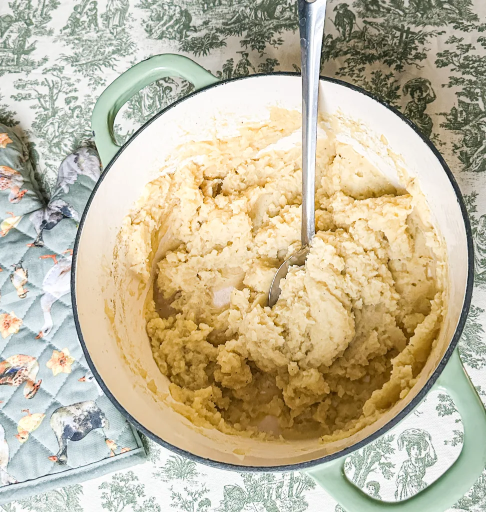 Dairy-free mased potatoes in a pot with a serving spoon, next to a pot holder.