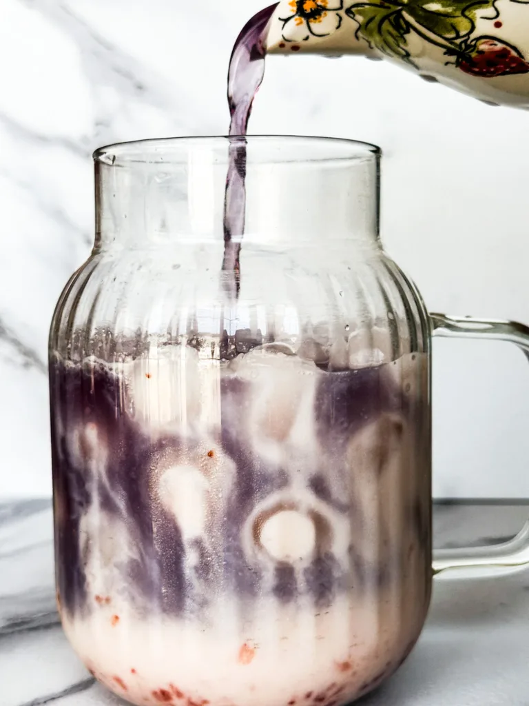 Purple tea being poured into the butterfly pea tea latte.