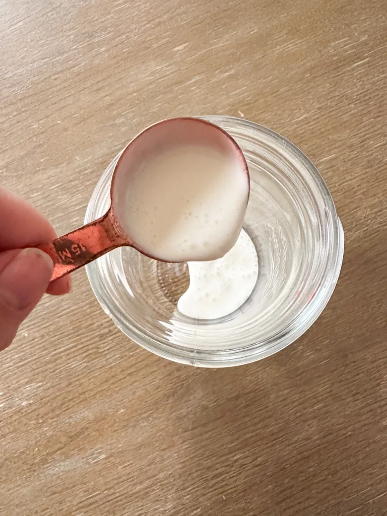 Heavy whipping cream being poured into a glass cup,