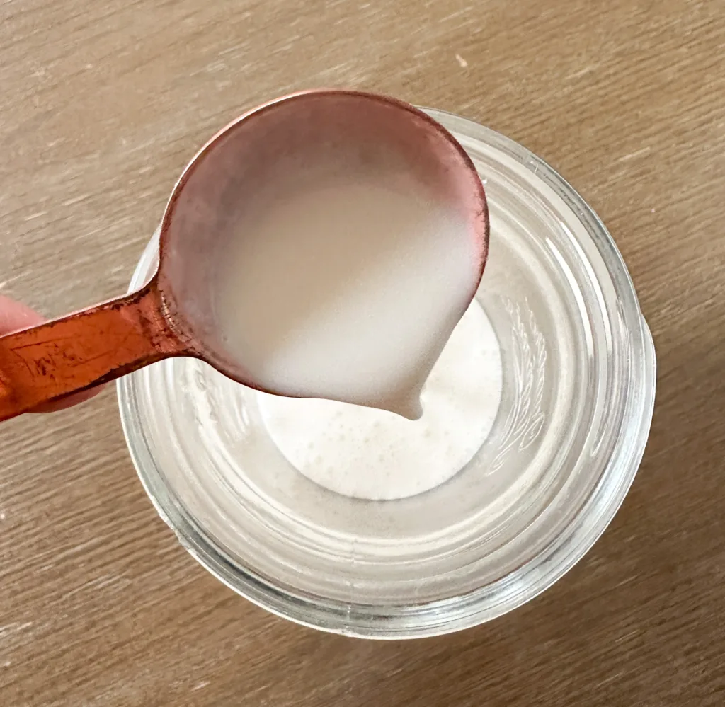Milk being poured into a glass jar.