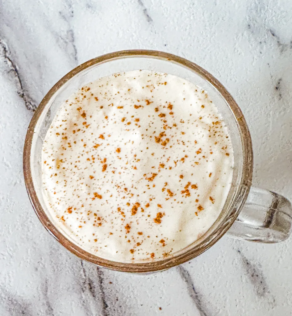 A close up of a cup with cold foam with cinnamon on top.