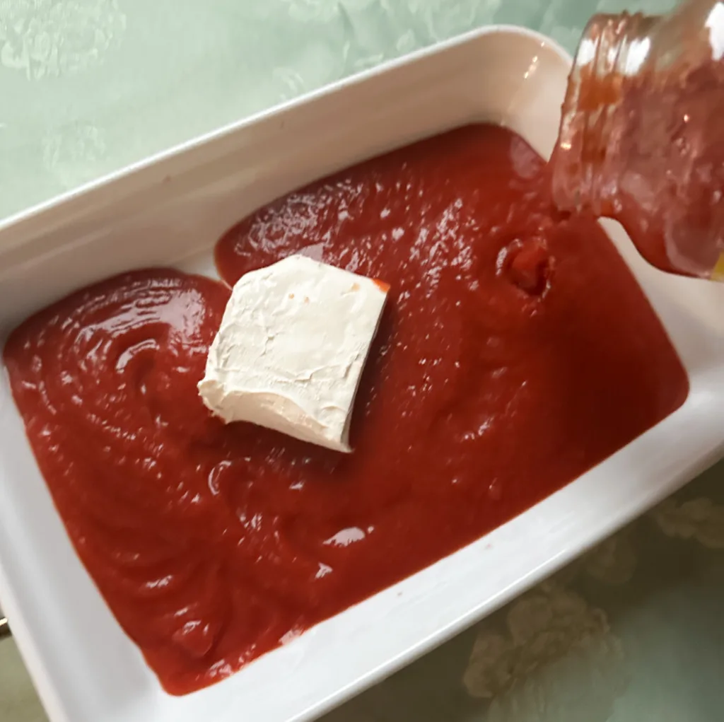 Marinara sauce being poured into a baking dish with cheese.