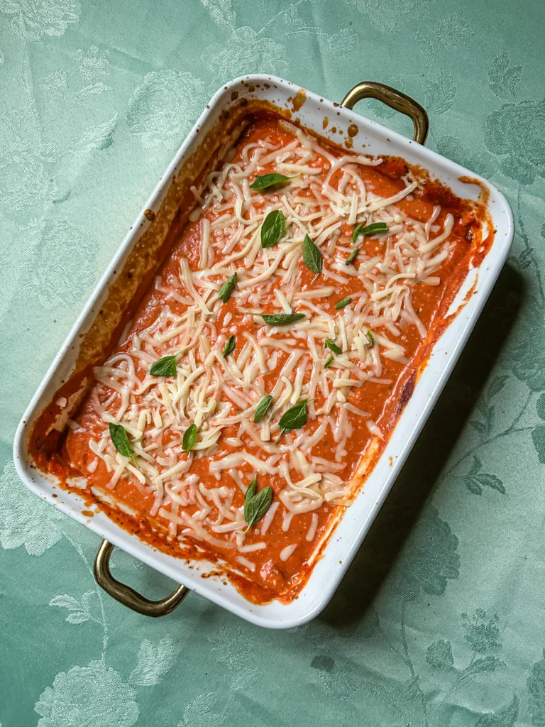 A pan of fresh-baked cheese in a pan with fresh basil on top.