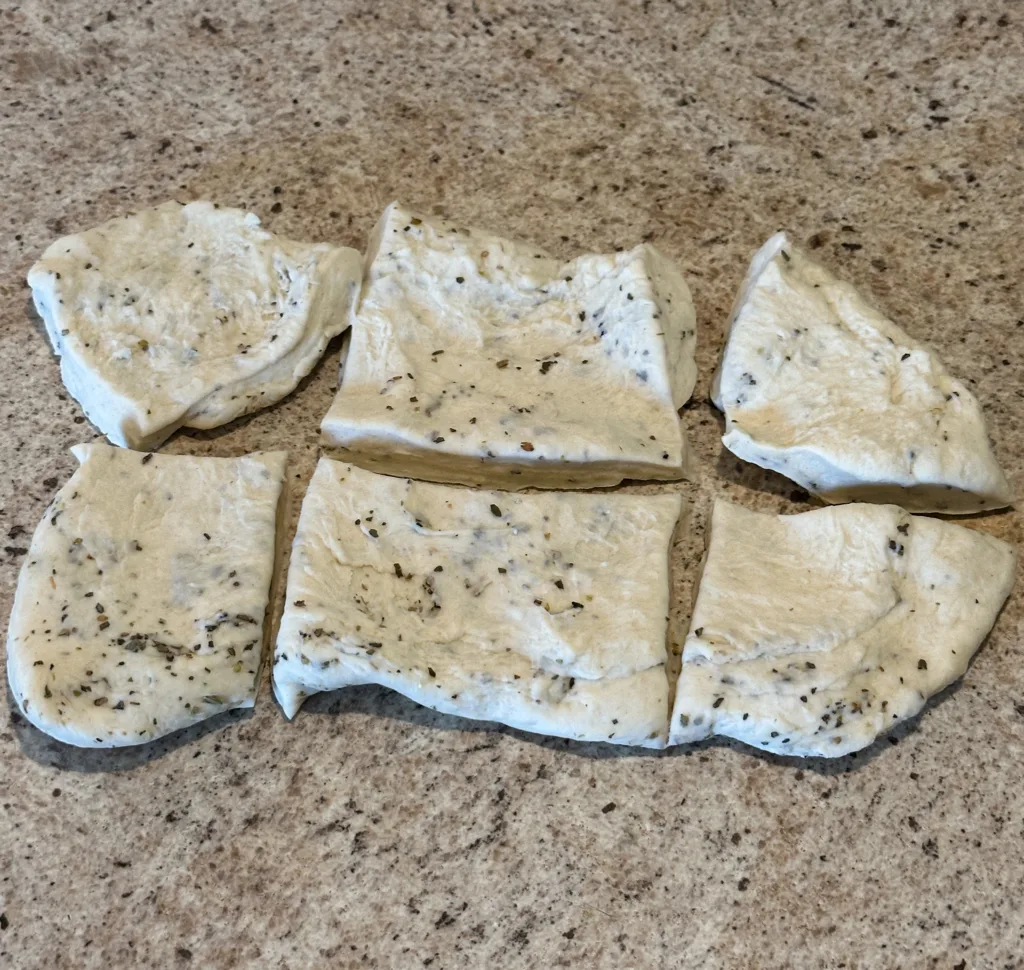 6 pieces of naan dough on a counter.