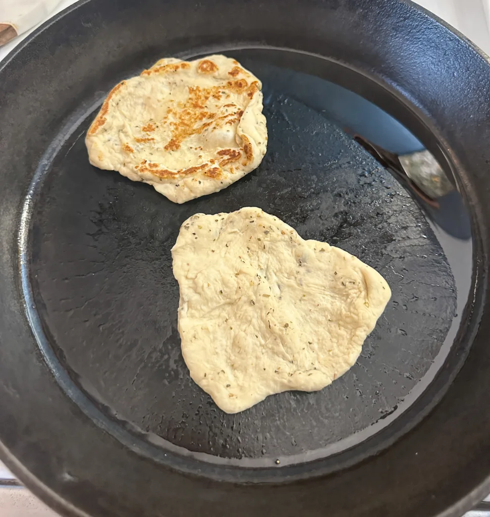 2 pieces of naan in a cast iron skillet.