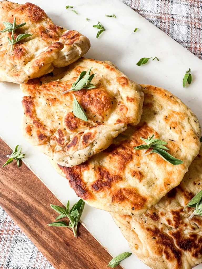 Homemade naan recipe close up picture on a cutting board with fresh oregano.