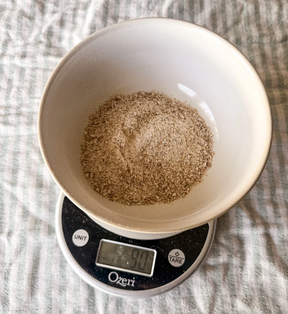 A kitchen scale with flour being measured on it.