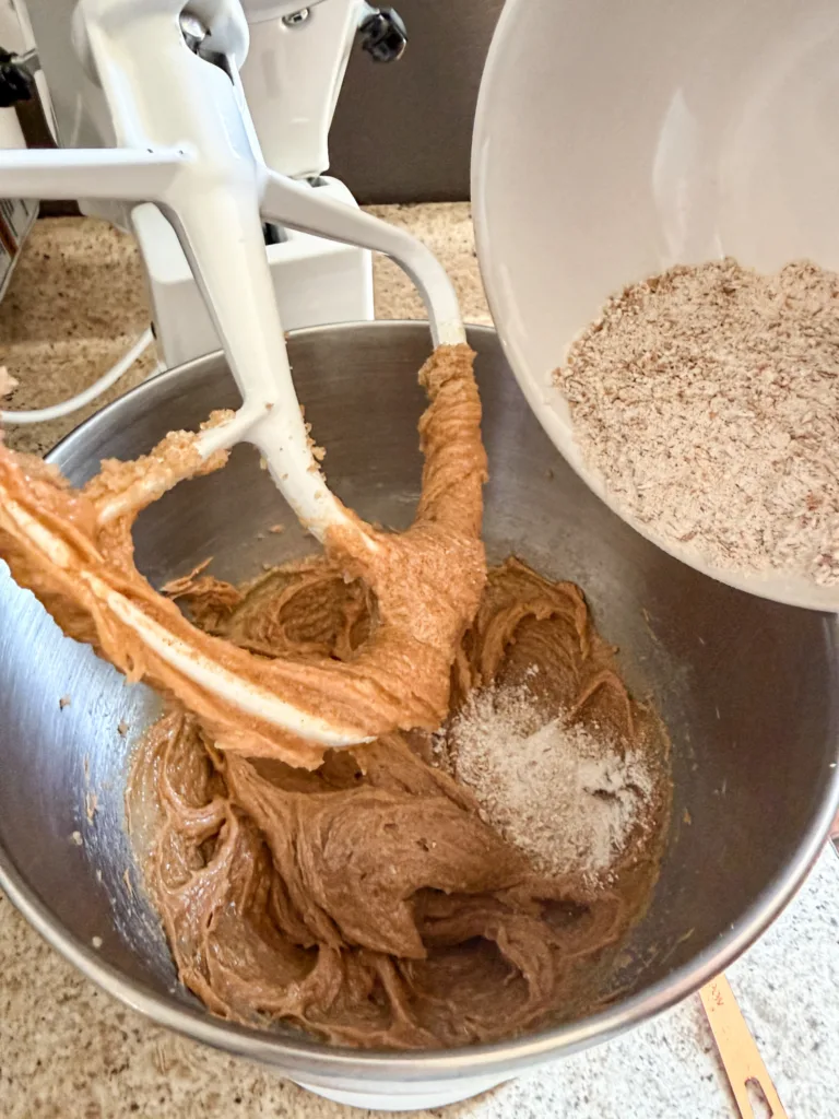 A stand mixer with einkorn flour being added to the peanut butter mixture.