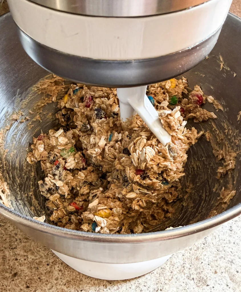 Oats, chocolate chips, and M&M's being added into the einkorn monster cookie dough.