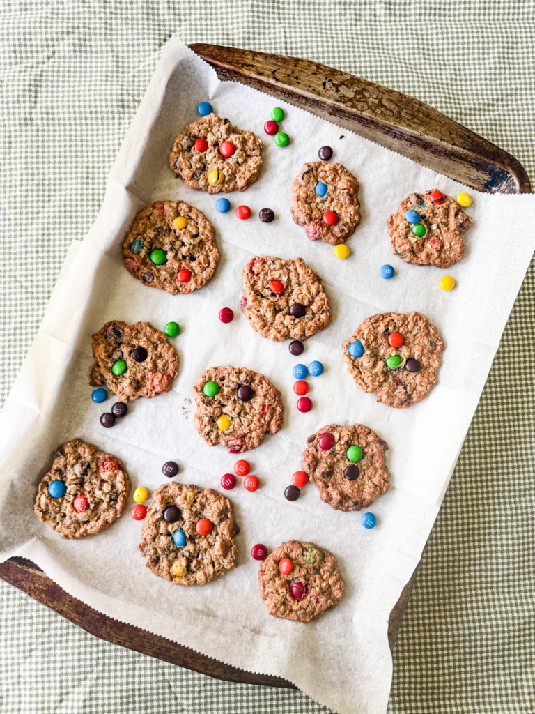 Einkorn monster cookies on a cookie sheet with M&M's on top of a table cloth. 