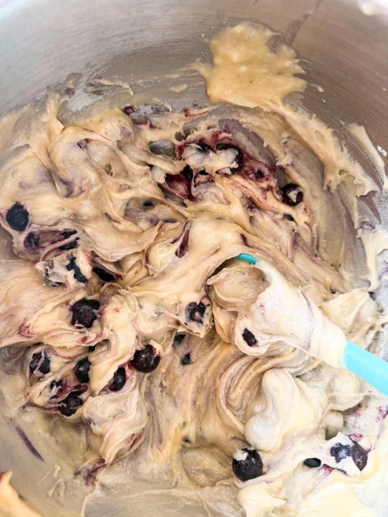 Muffin batter with blueberries being folded into it.