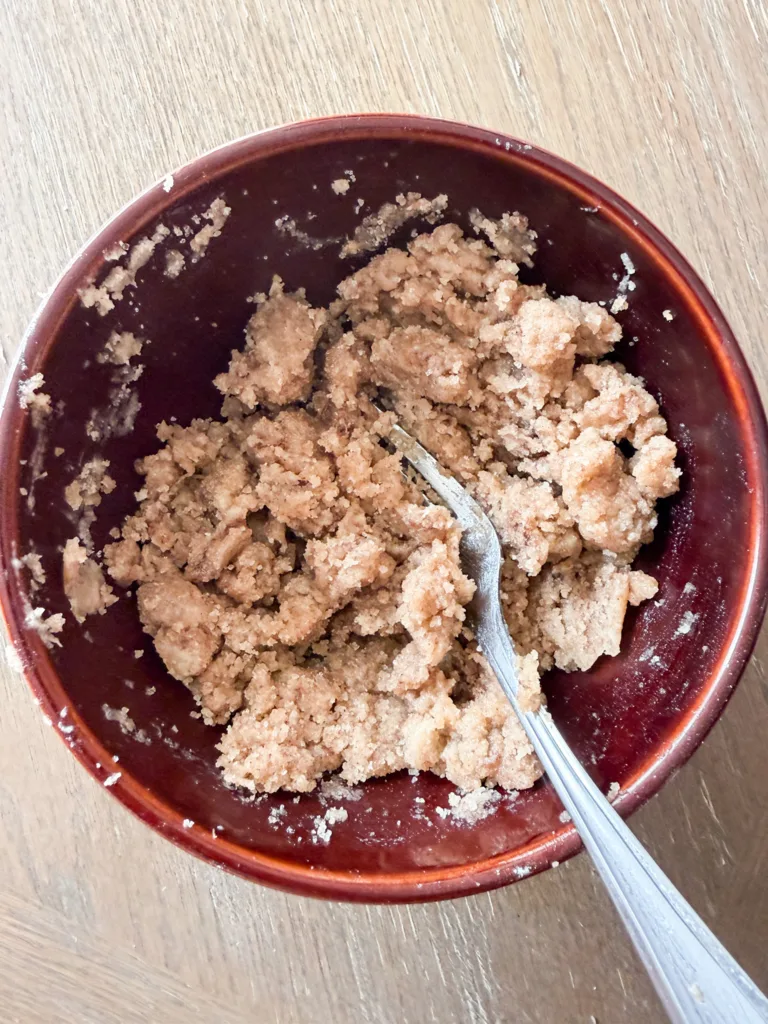 A bowl with a streusel mixture in it with a fork.