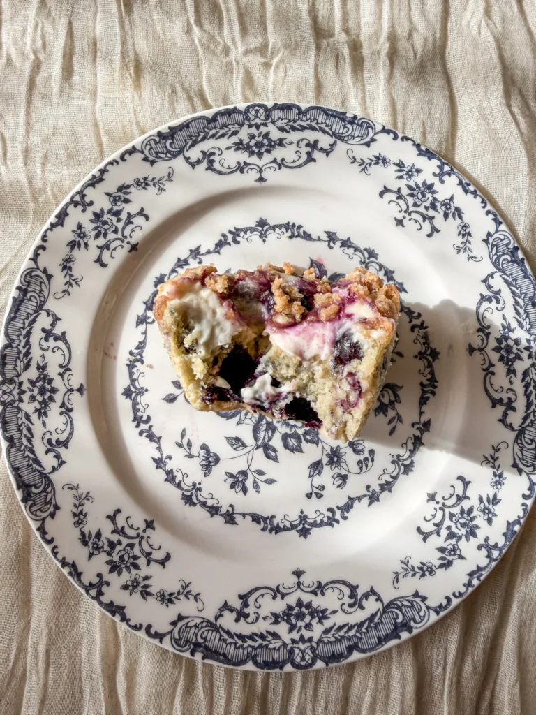A half of a  blueberry cream cheese muffin on a plate.