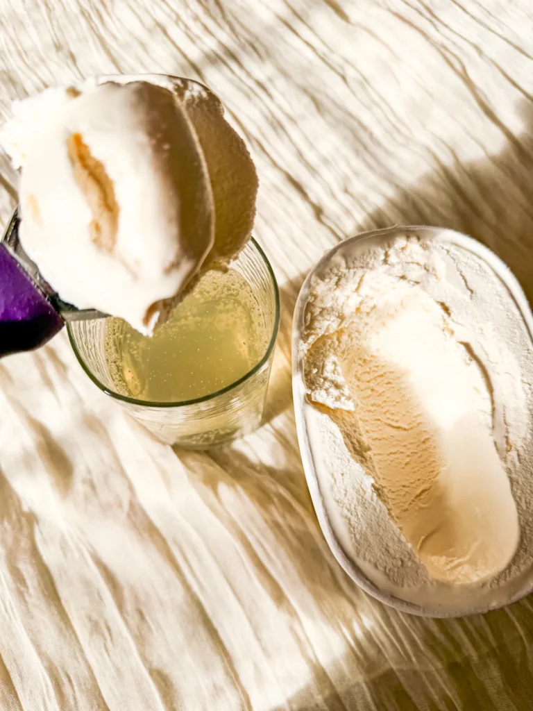 Vanilla ice cream being added to a glass of pop.