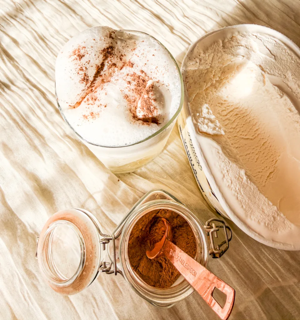 A glass with pop and ice cream in it, topped with cinnamon.
