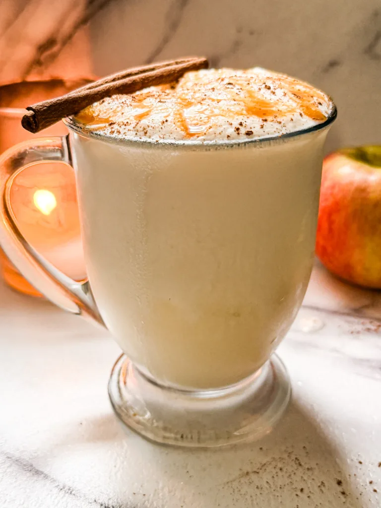 Apple dirty soda float with cinnamon, a cinnamon stick, and caramel on it.